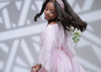 Woman in a pink dress standing on a floor with white geometric patterns.