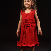 Primrose · Edition Two — girl in a deep scarlet eucalyptus fibre frock holding coloured balls, showing the tiered ruffle bodice